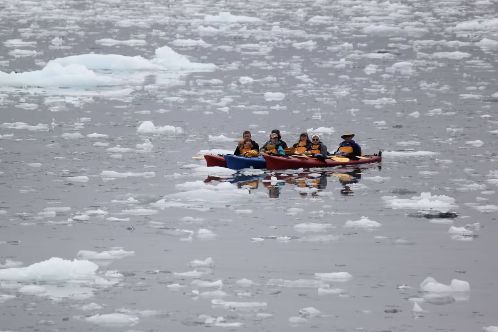 Kayakers paddling through glacial ice